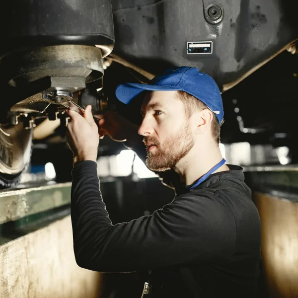Auto mechanic working on vehicle in workshop setting