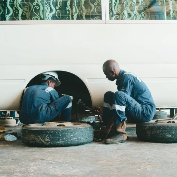 Two auto mechanics working on repairing a vehicle's wheel
